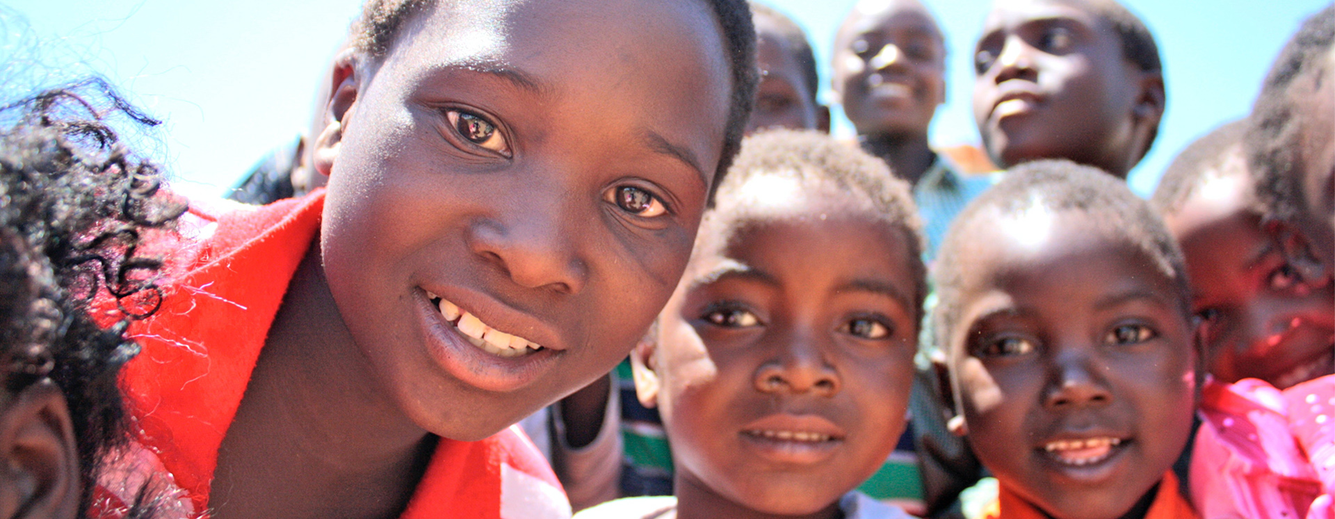 Bright, smiling children in our education outreach — orphans and vulnerable children supported by Held at Heart Uganda in Wakiso and Kampala.