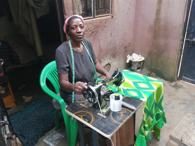 Participant at vocational tailoring training seated at a sewing machine with patterned fabric — Held at Heart Uganda, Wakiso.